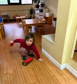 Lyonsgate Montessori School Toddler student developing hand-eye coordination and motor skills by trying to toss bean bags into square.