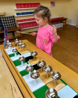 Lyonsgate Montessori School Casa student using the Montessori Bells material that helps to develop auditory discrimination skills and is an introduction to musical composition.
