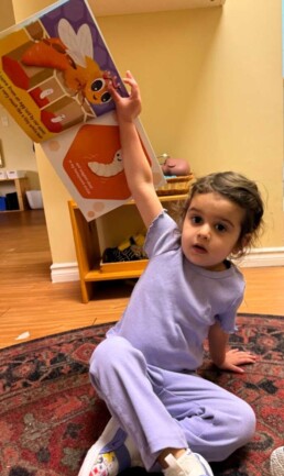 Lyonsgate Montessori School Toddler student showing the book about bees she is 