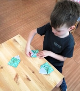 Lyonsgate Montessori School Casa student folding envelopes for his class to use to keep small work safe.