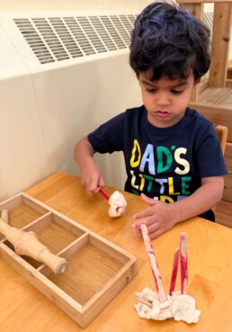 Lyonsgate Montessori School Toddler student building the hand strength needed for further motor skills development with playdough.