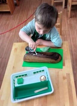 Lyonsgate Montessori School Casa student engaged in the Montessori Polishing Wood activity to develop concentration and to achieve visual success by following a multi-step process.