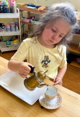 Lyonsgate Montessori School Casa student pouring water for tea, which is an extension of traditional Montessori pouring activities that build hand eye coordination and control.