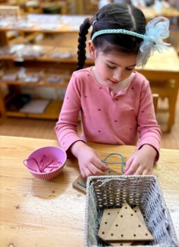 Lyonsgate Montessori School Casa student building fine motor skills and concentration while developing familiarity with geometric shapes.