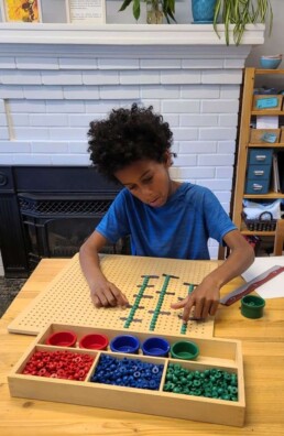 Lyonsgate Montessori School Elementary student working to find the lowest common multiple with Montessori manipulative materials.