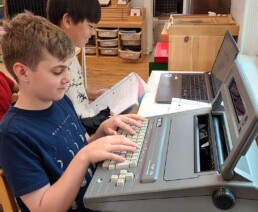 A Lyonsgate Montessori School Elementary student experiencing a little technological time travel with a typewriter.