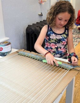 Lyonsgate Montessori School Elementary student weaving on the giant loom.