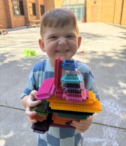 Lyonsgate Montessori School Toddler student with his bristle block creation on a sunny day recess.