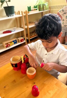 Lyonsgate Montessori School Toddler student exploring the different sizes of the nesting doll, working on problem-solving skills and sequencing.