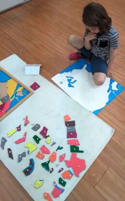 Lyonsgate Montessori School Casa student puzzling out a Montessori Puzzle Map.