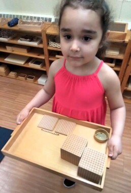 Lyonsgate Montessori School Casa student being introduced to quantities in the decimal system with the Montessori Golden Beads material.